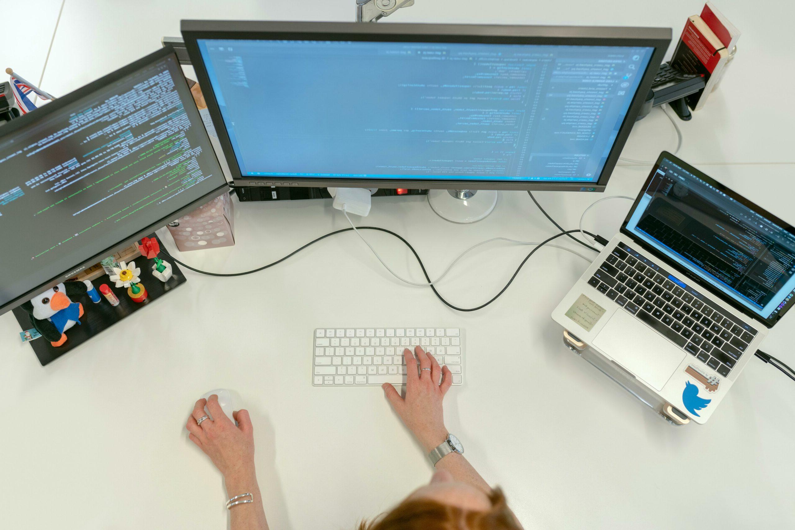 一个女人在她的工作台上使用三台电脑